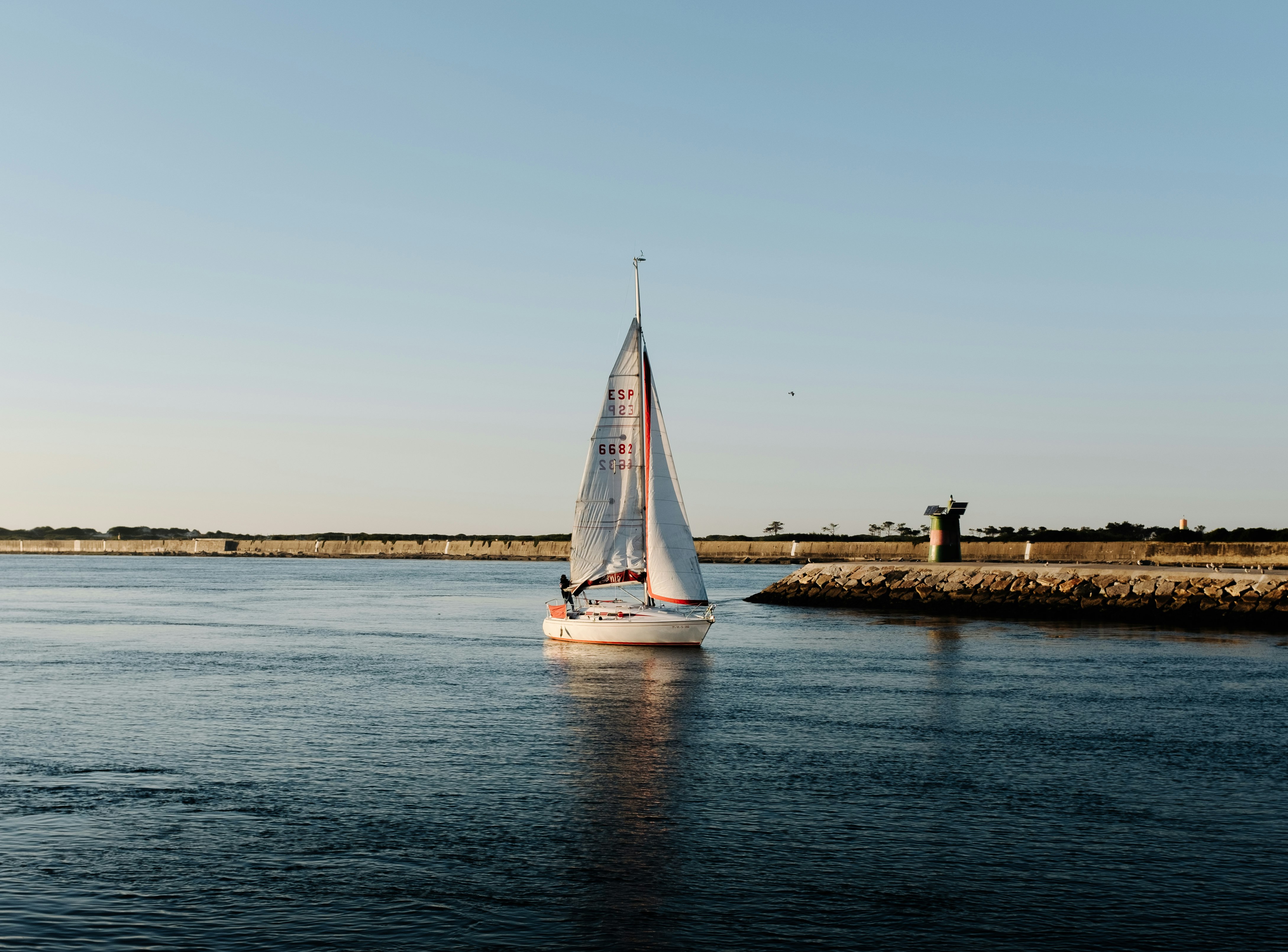 white sailboat on sea under white sky during daytime